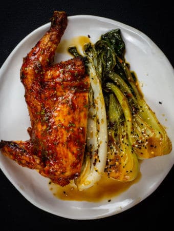 1/2 chicken, asian veg on a white plate