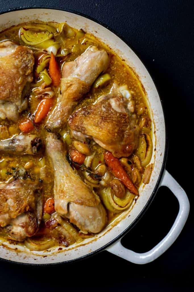 Cooked chicken cassoulet in white shallow proof casserole dish