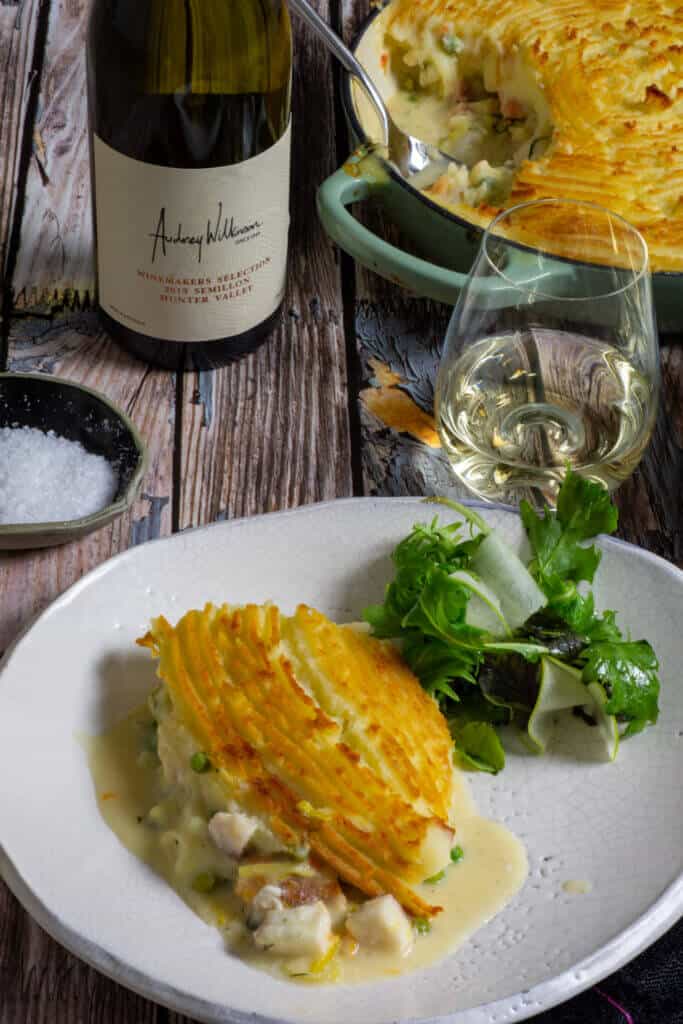 fish pie, glass of wine, wine bottle and salad