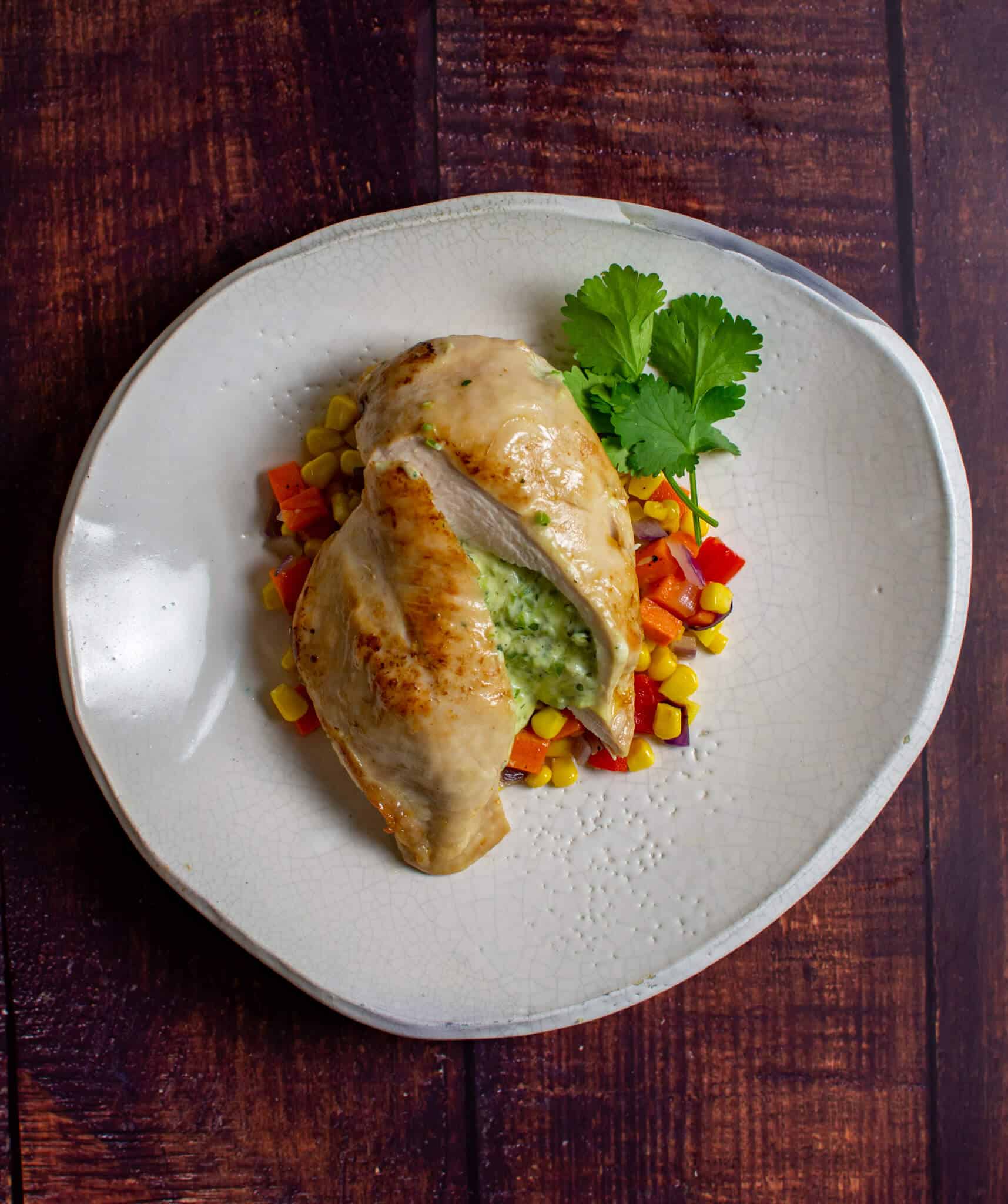 jalapeno popper stuffed chicken on white plate with corn hash
