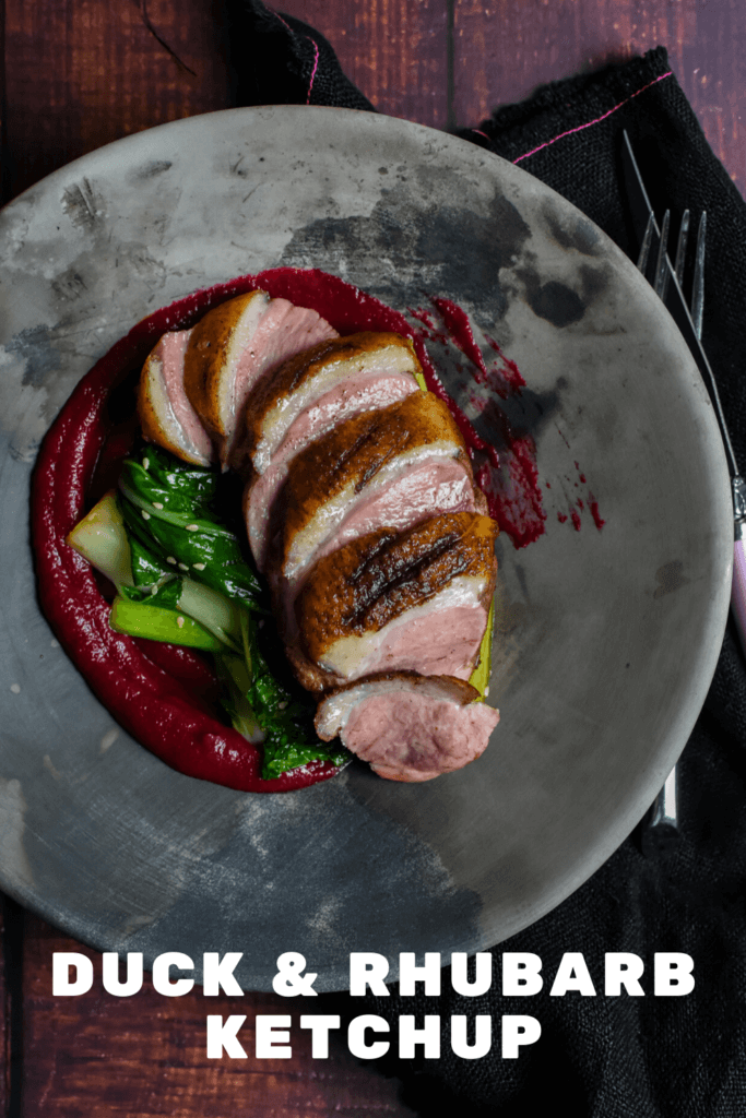 Duck breast, rhubarb ketchup & asian greens in a made of australia bowl on a table