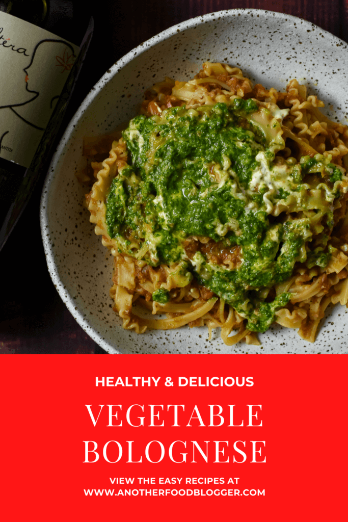 vegetable bolognese with basil pesto & creme fraiche in a bowl and bottle of wine