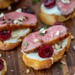 duck crostinis with cherries & goat cheese on wooden chopping board
