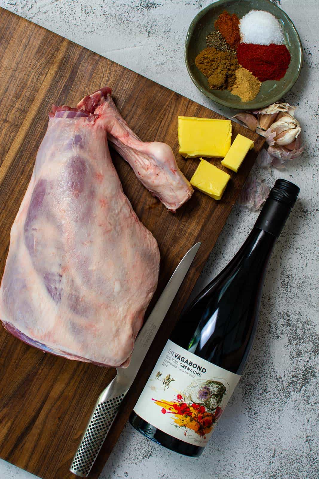 whole leg of lamb on a global chopping board with Thistledown vagabond grenache next to it