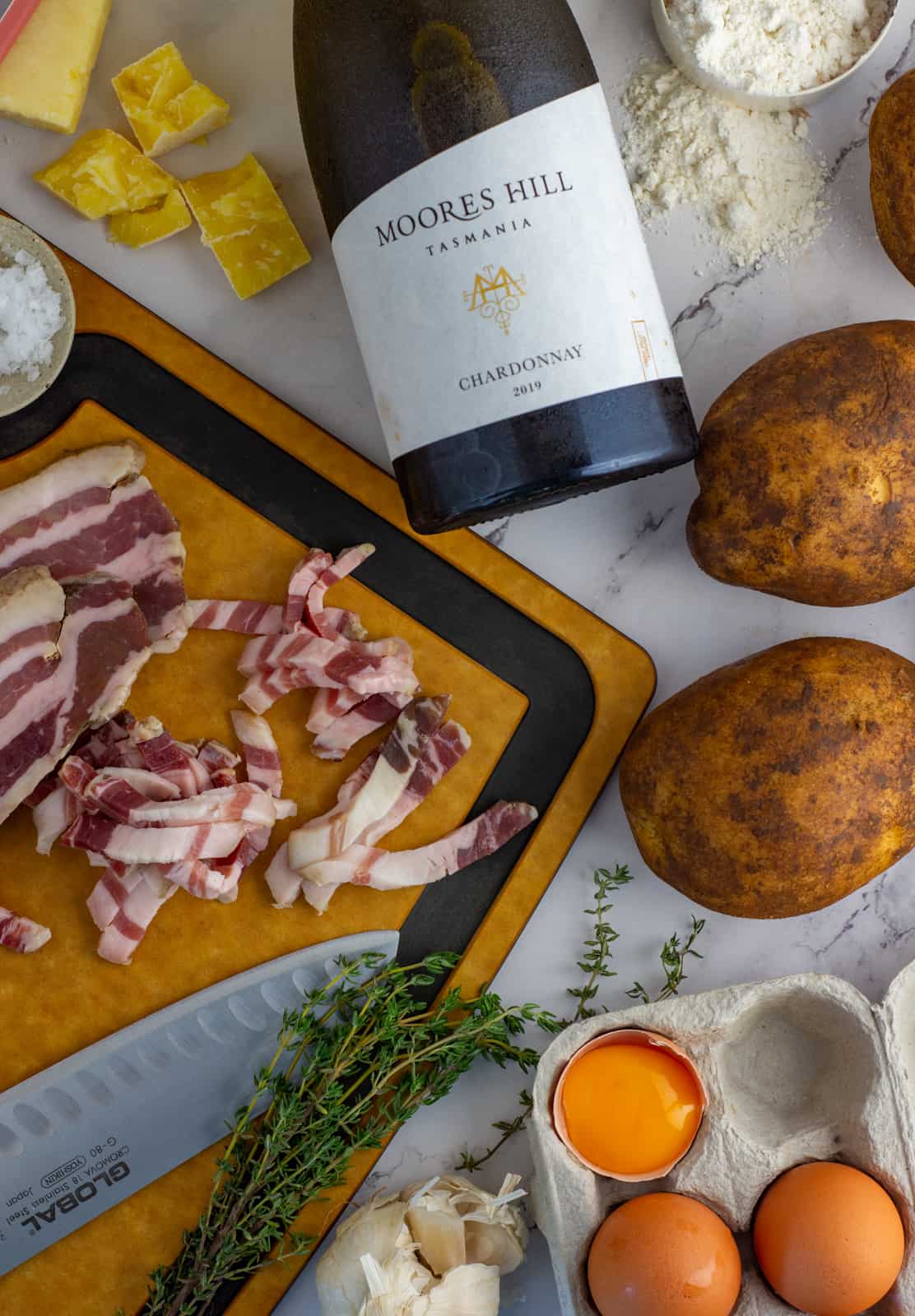 moores hill chardonnay, potatoes, eggs, thyme & pancetta on a chopping board