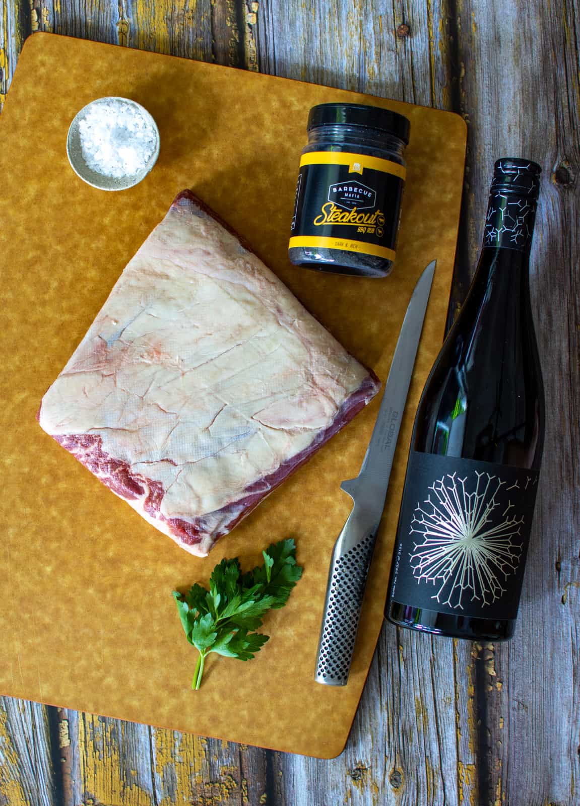 short ribs on a chopping board with barbecue madia rub and a bottle of dandelion wine