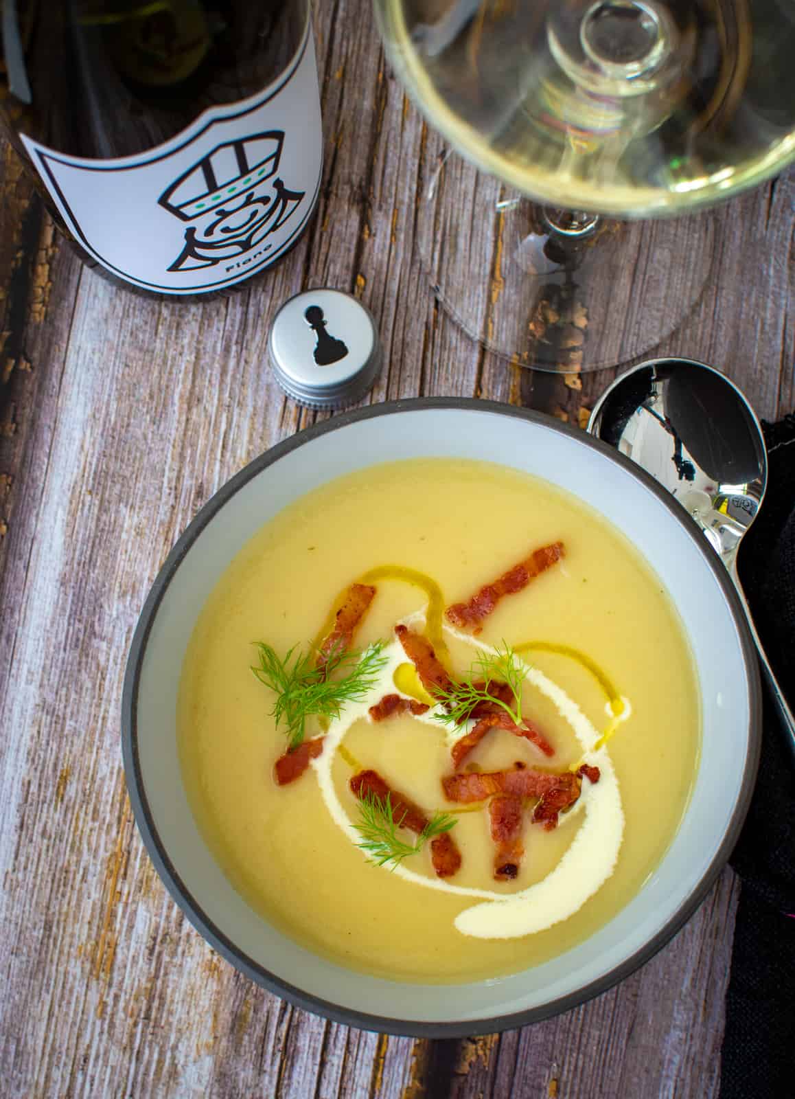 A bowl of parsnip soup with bacon, fennel frinds and cream on top