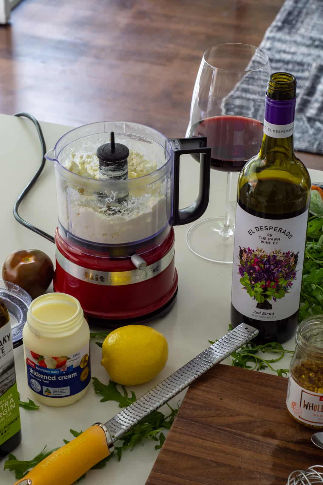 goat cheese in a blender with cream, lemon and a bottle of wine on counter top 
