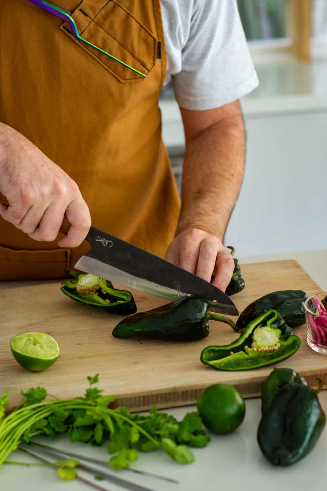 Someone cutting poblano peppers with a chef knife 