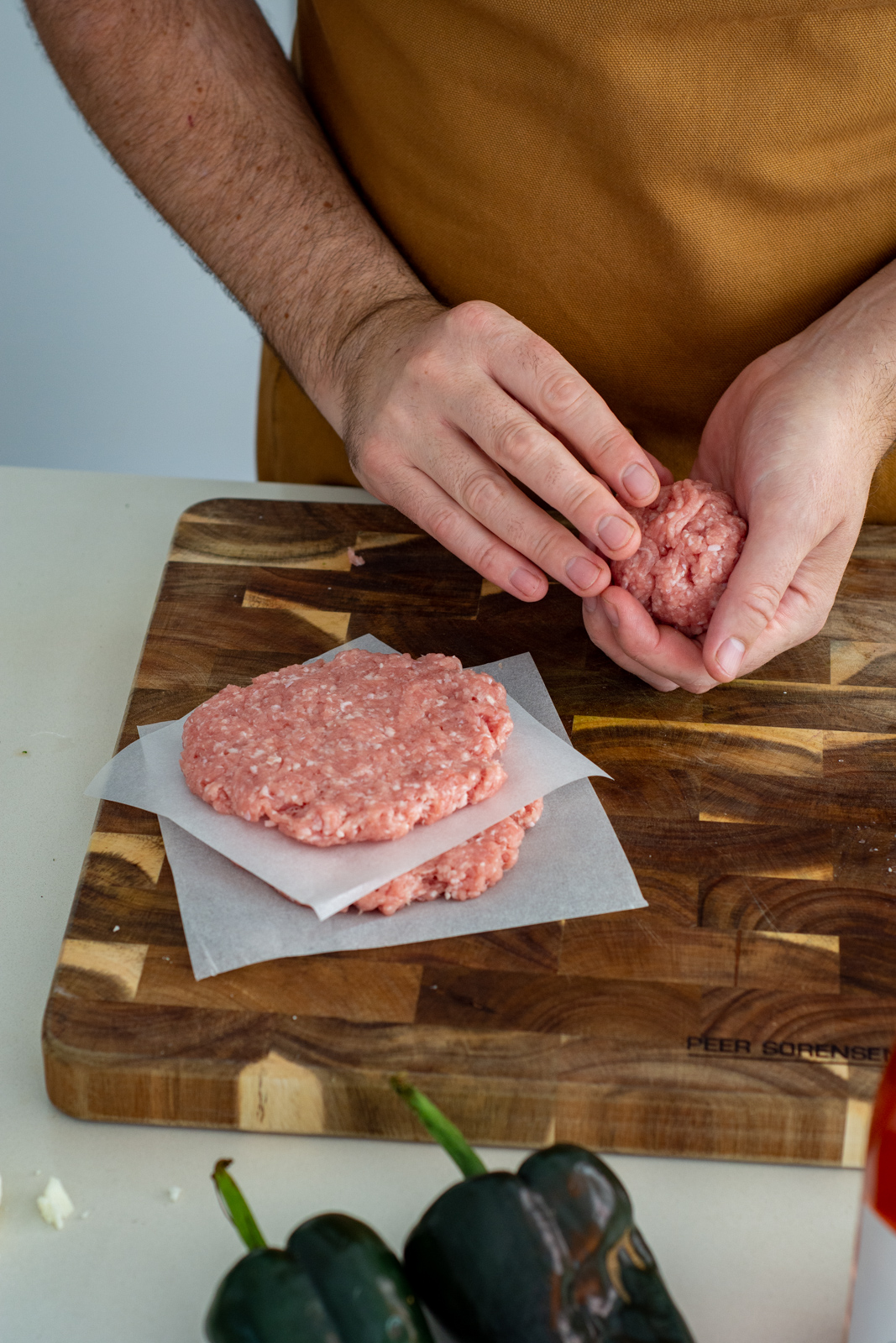 someone forming pork burger patties on a chopping board 