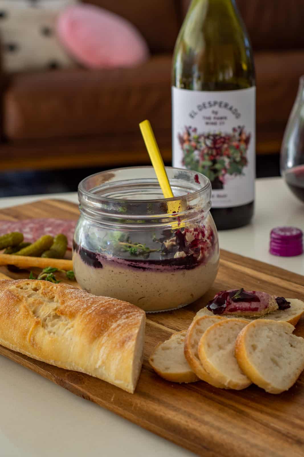 simple mushroom pate on a table with baguette next to the jar and wine in background