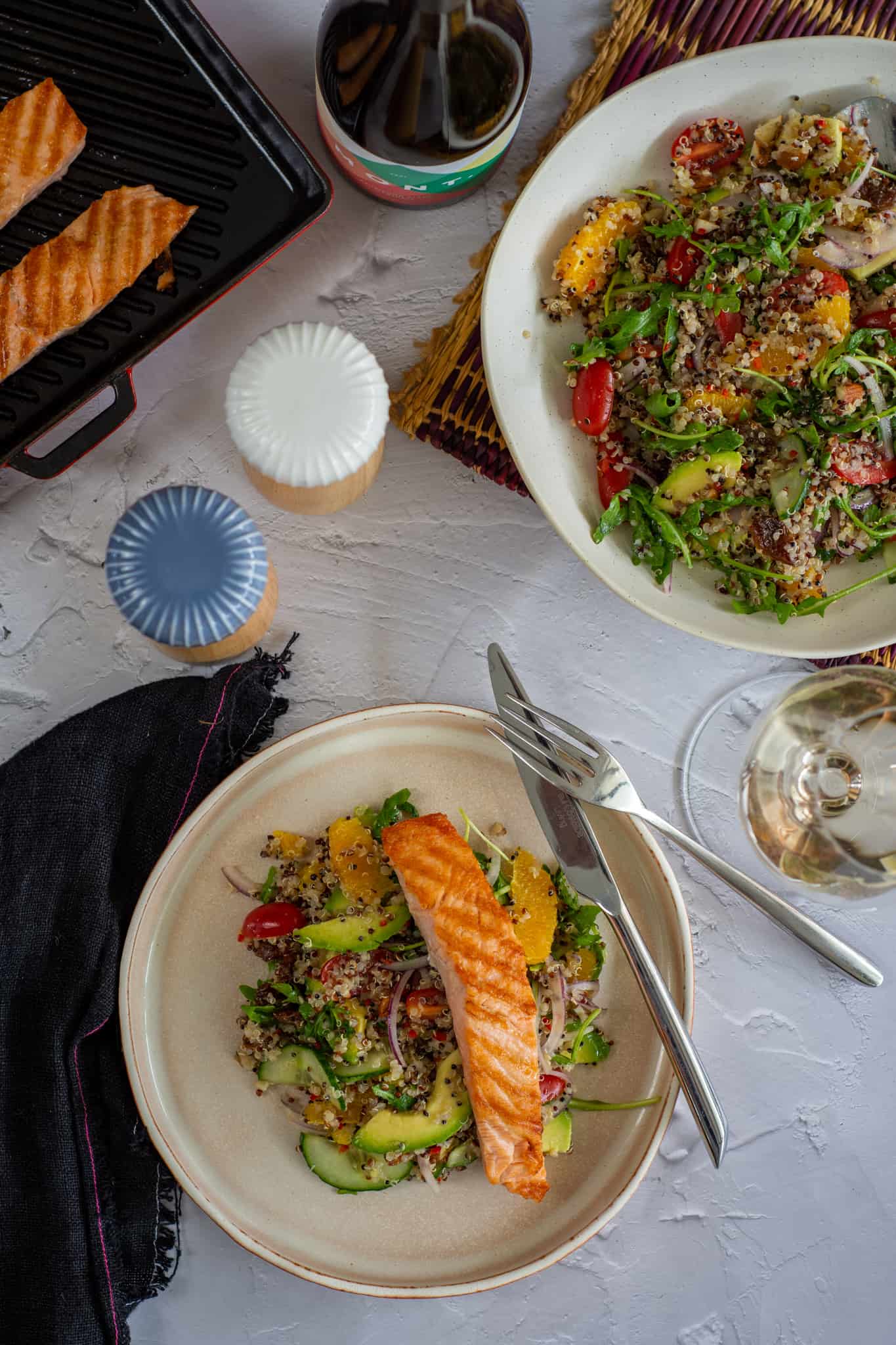 ancient grain salad with grilled salmon on a plate, with wine and a salad bowl on table too