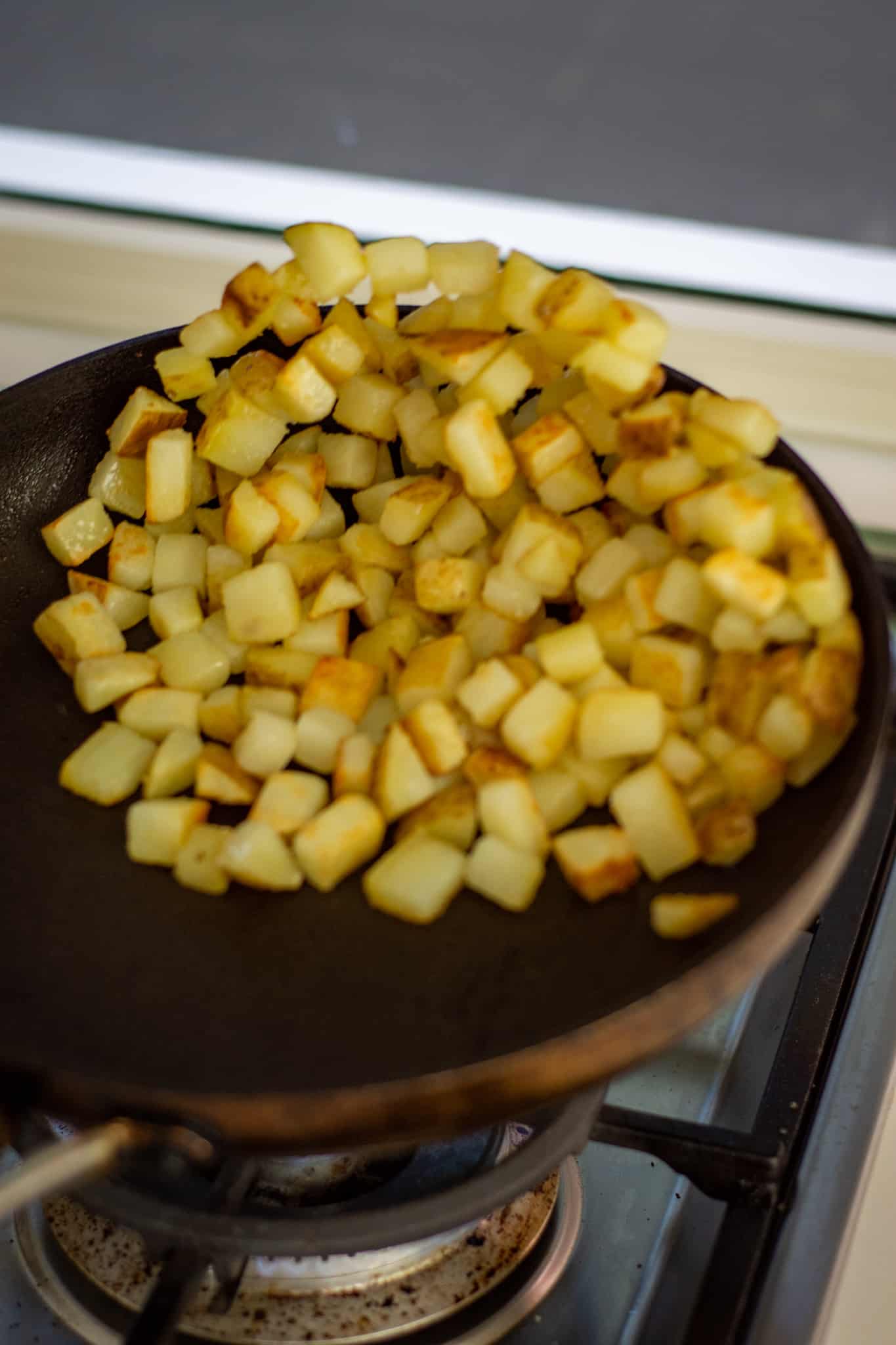tossing potatoes in a fryin pan 