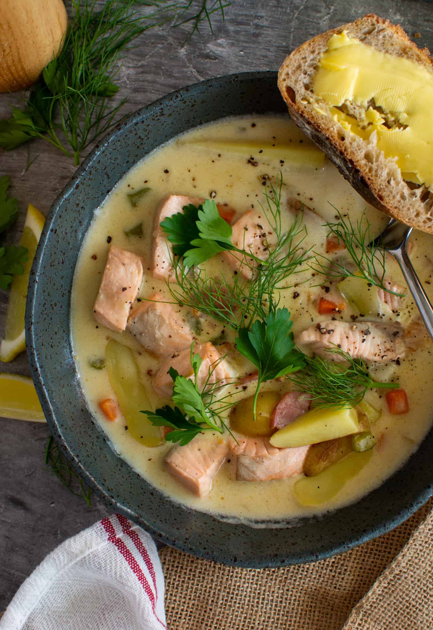 birdseye view of a bowl of salmon chowder with a slice of buttered bread on the side of the bowl