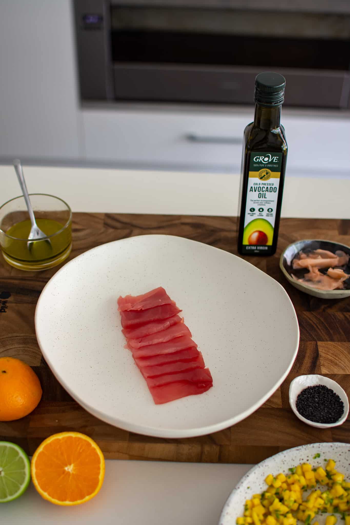 a photo of sliced tuna on a plate in the kitchen with other food beside it